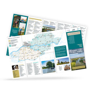 Spread of a colorful travel brochure with maps, photos, and text in Dutch, shown at a tilted angle on a white background.