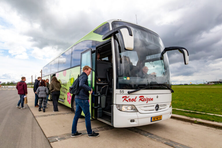 Een groep mensen stapt in een touringcar van Krol Reizen.